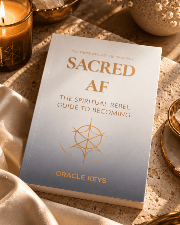 Sacred AF paperback with ivory-to-charcoal cover and gold lettering in a warm candlelit editorial still life